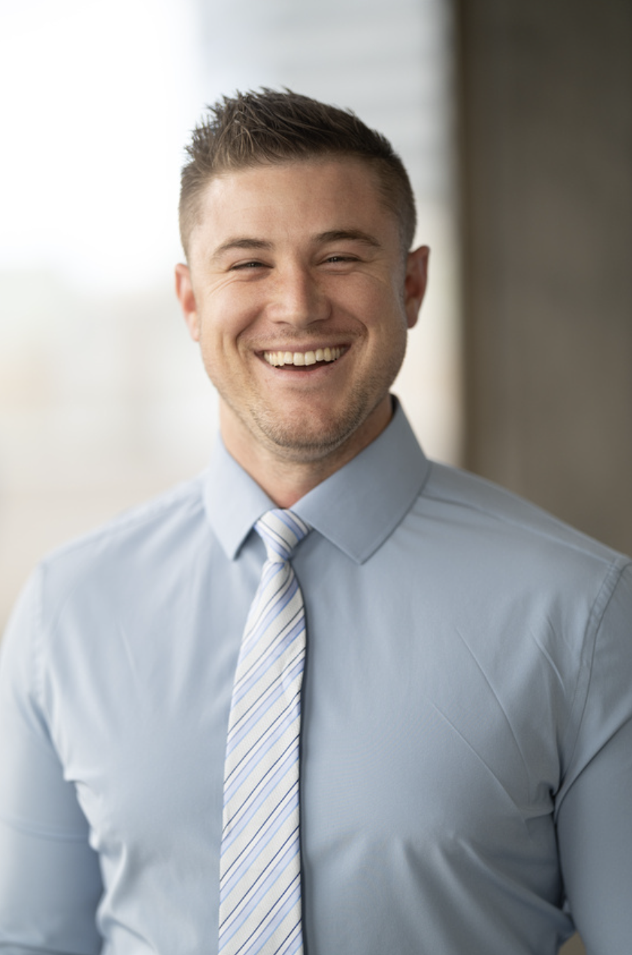 Man in blue shirt and tie smiling